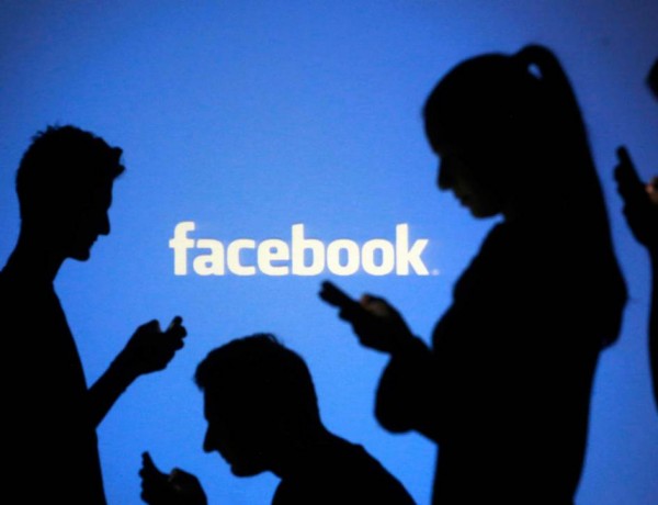 People are silhouetted as they pose with laptops in front of a screen projected with a Facebook logo, in this picture illustration taken in Zenica October 29, 2014. Facebook Inc warned on Tuesday of a dramatic increase in spending in 2015 and projected a slowdown in revenue growth this quarter, slicing a tenth off its market value. Facebook shares fell 7.7 percent in premarket trading the day after the social network announced an increase in spending in 2015 and projected a slowdown in revenue growth this quarter.   REUTERS/Dado Ruvic (BOSNIA AND HERZEGOVINABUSINESS LOGO - Tags: BUSINESS SCIENCE TECHNOLOGY LOGO TPX IMAGES OF THE DAY)