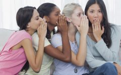 Friends whispering secret to shocked brunette