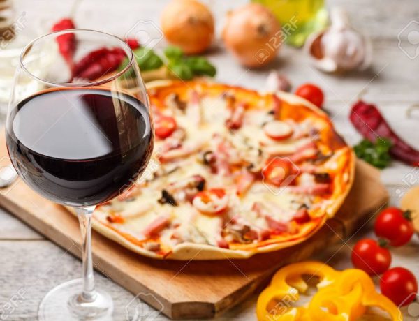 Glass of red wine with pizza on cutting board