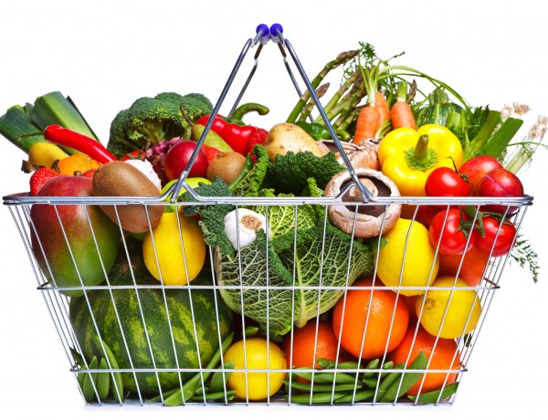 Photo of a wire shopping basket full of fresh fruit and vegetables, isolated on a white background.