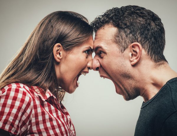 Angry young couple shouting face to face.