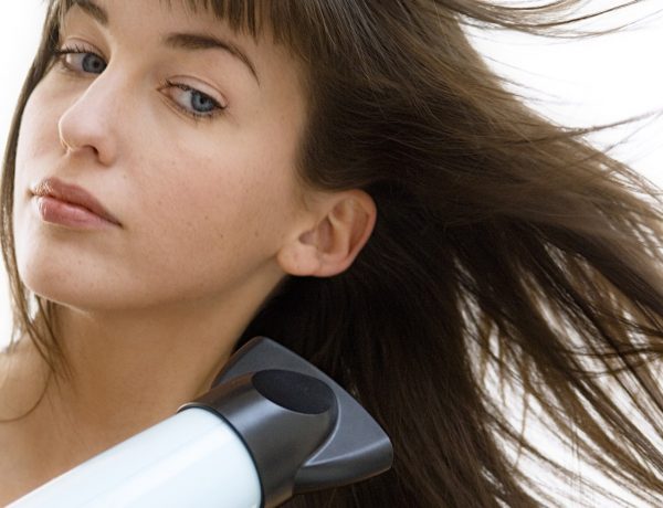 Portrait of a young woman using a hair drier