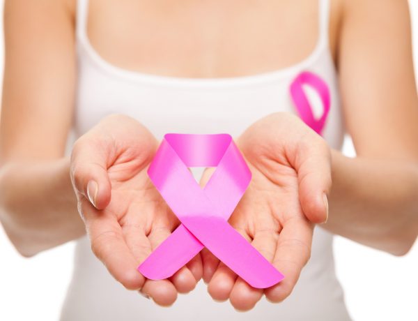 Woman holding a pink cancer awareness ribbon in her hands